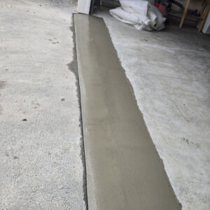 Newly poured concrete apron at residential garage entrance with smooth, level finish